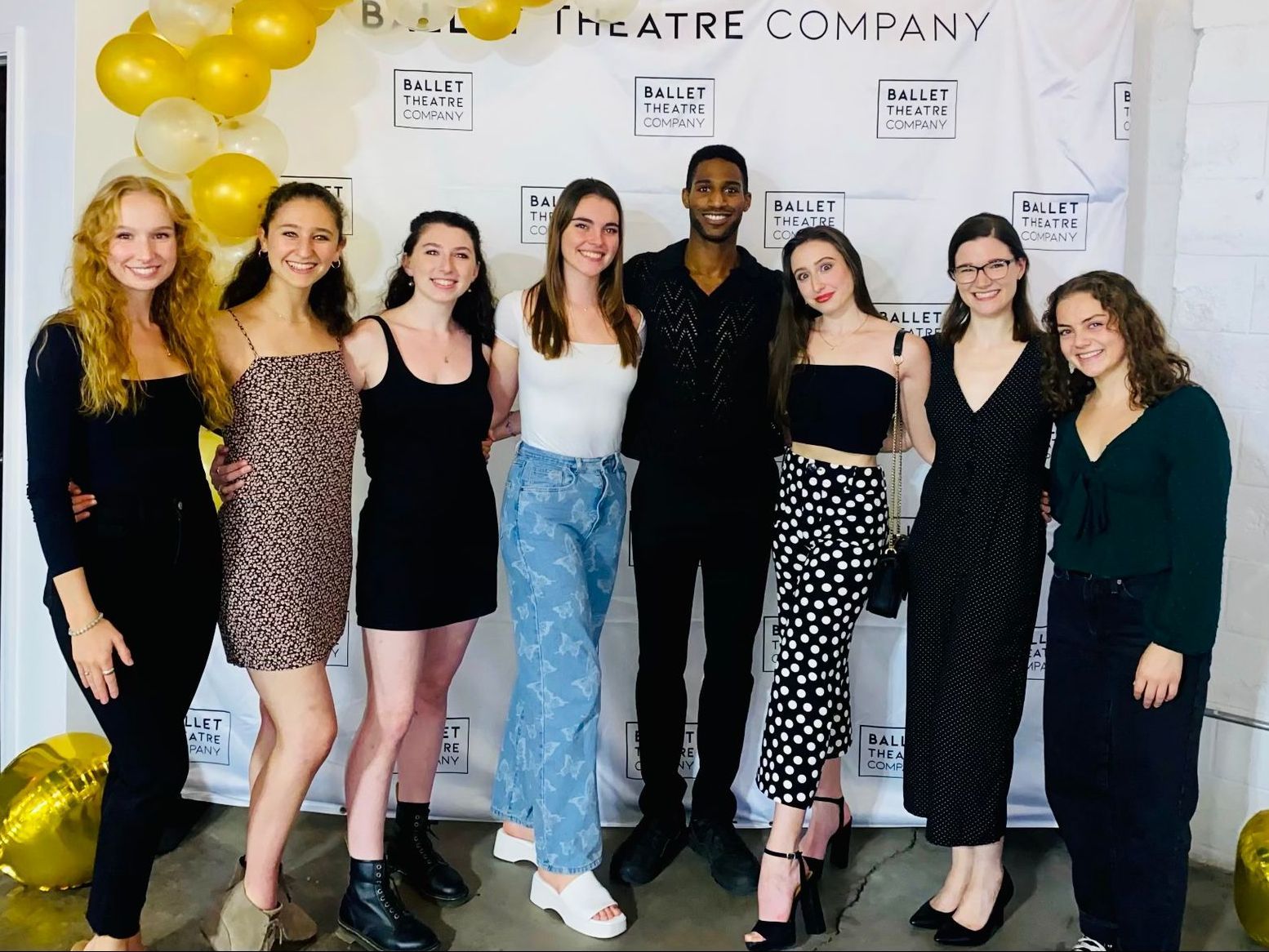 a group of people are posing for a picture in front of a theatre company backdrop .